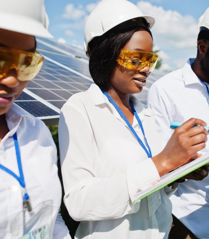 African american technician checks the maintenance of the solar panels. Group of three black engineers meeting at solar station.