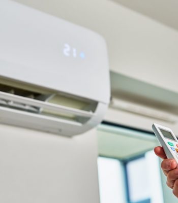 Hand adjusting temperature on air conditioner Hand adjusting temperature on air conditioner with remote control, Working air conditioner for comfort temperature in home at hot summer